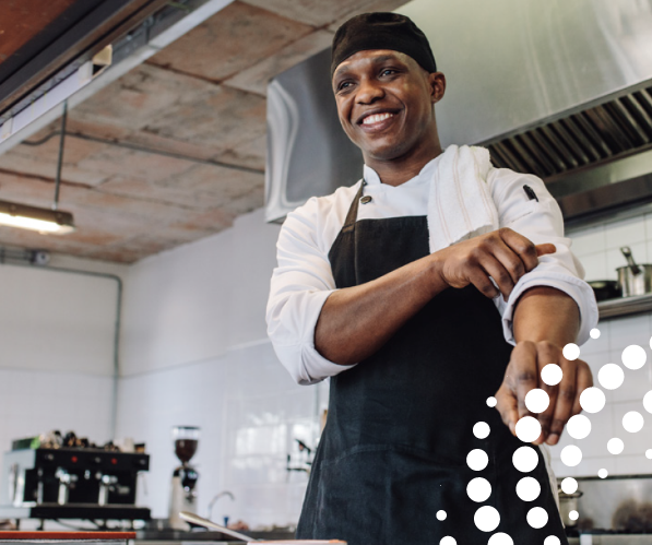 Image of a chef smiling in a kitchen whilst rolling up his sleeve