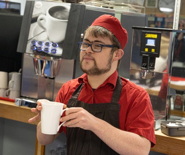 Image of a chef smiling in a kitchen whilst rolling up his sleeve