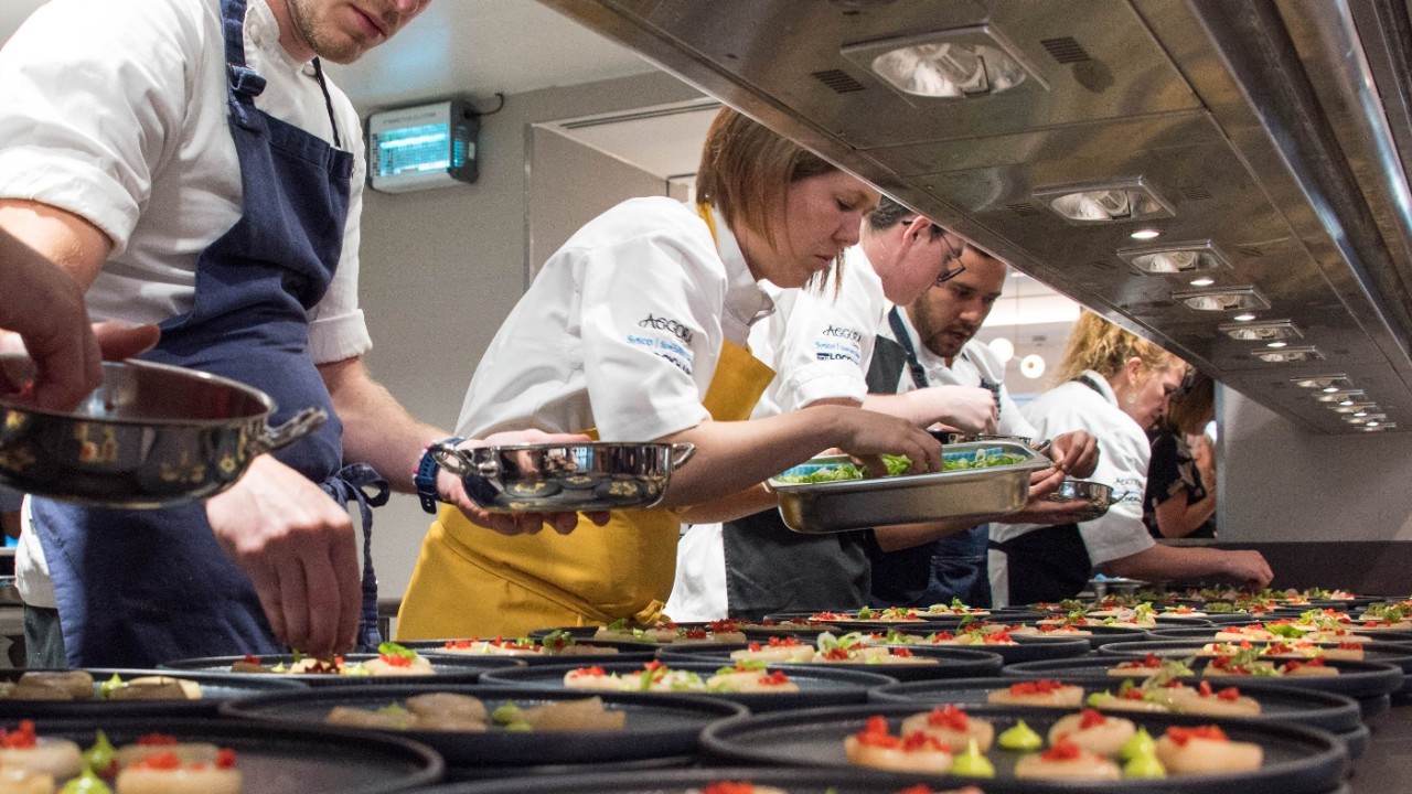 Apprentices in a kitchen plating and serving food