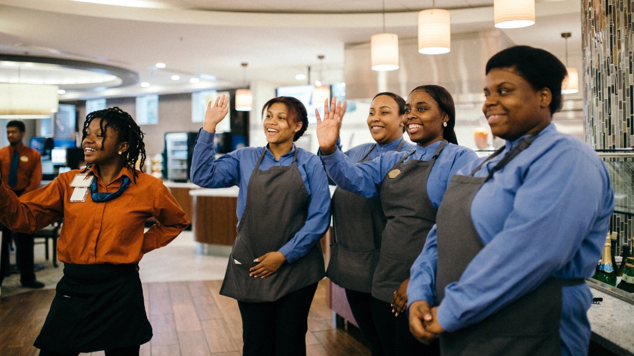 Colleagues in a team meeting raising their hands and smiling