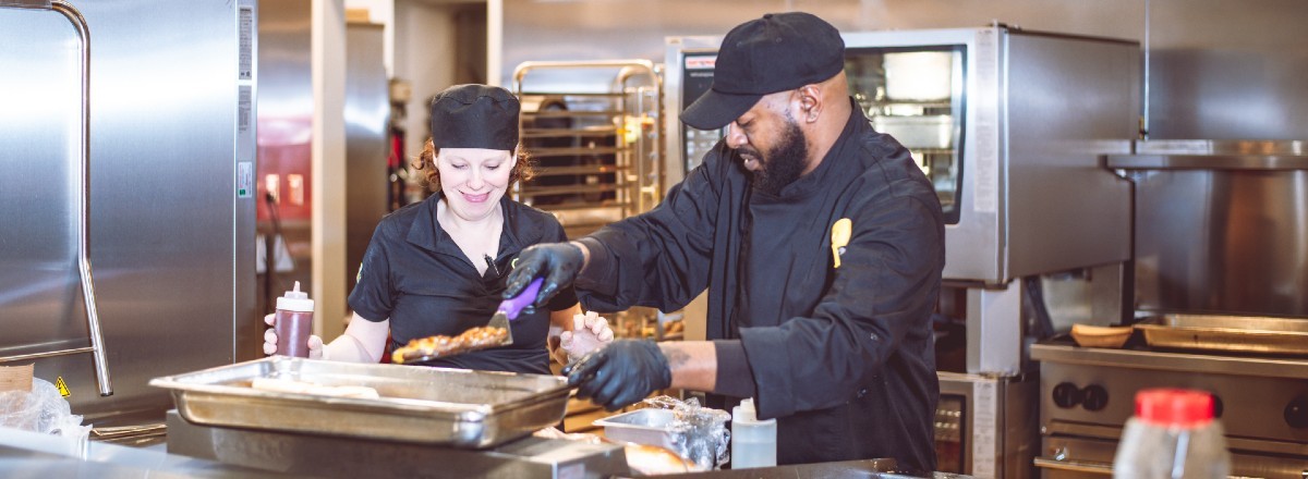 Compass chefs working in the kitchen, wearing food preparation gloves